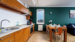 Ett modernt kök med träskåp, en diskho i rostfritt stål och en matplats med ett träbord och stolar.
