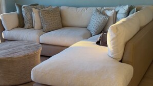 A living room with a sectional sofa, a round coffee table, and a ceiling fan. - 2-Bedroom Beachfront Condo on Private Beach Longboat Key (Longboat Key)