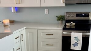A modern kitchen with white cabinets, a stainless steel oven, and a microwave. - 2-Bedroom Beachfront Condo on Private Beach Longboat Key (Longboat Key)