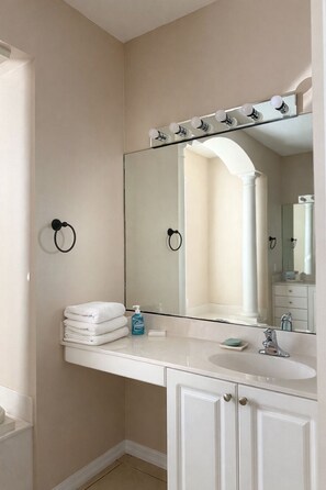 Un bagno con uno specchio grande, un lavandino e un portasciugamani.