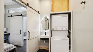 A modern bathroom with a mirror, a sink, and a washing machine.