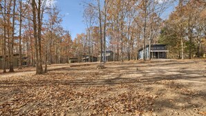 A campground with multiple cabins, surrounded by trees and covered in fallen leaves.