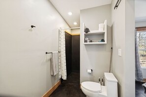 Ein Badezimmer mit Toilette, Waschbecken, Handtuchhalter und Duschvorhang.
