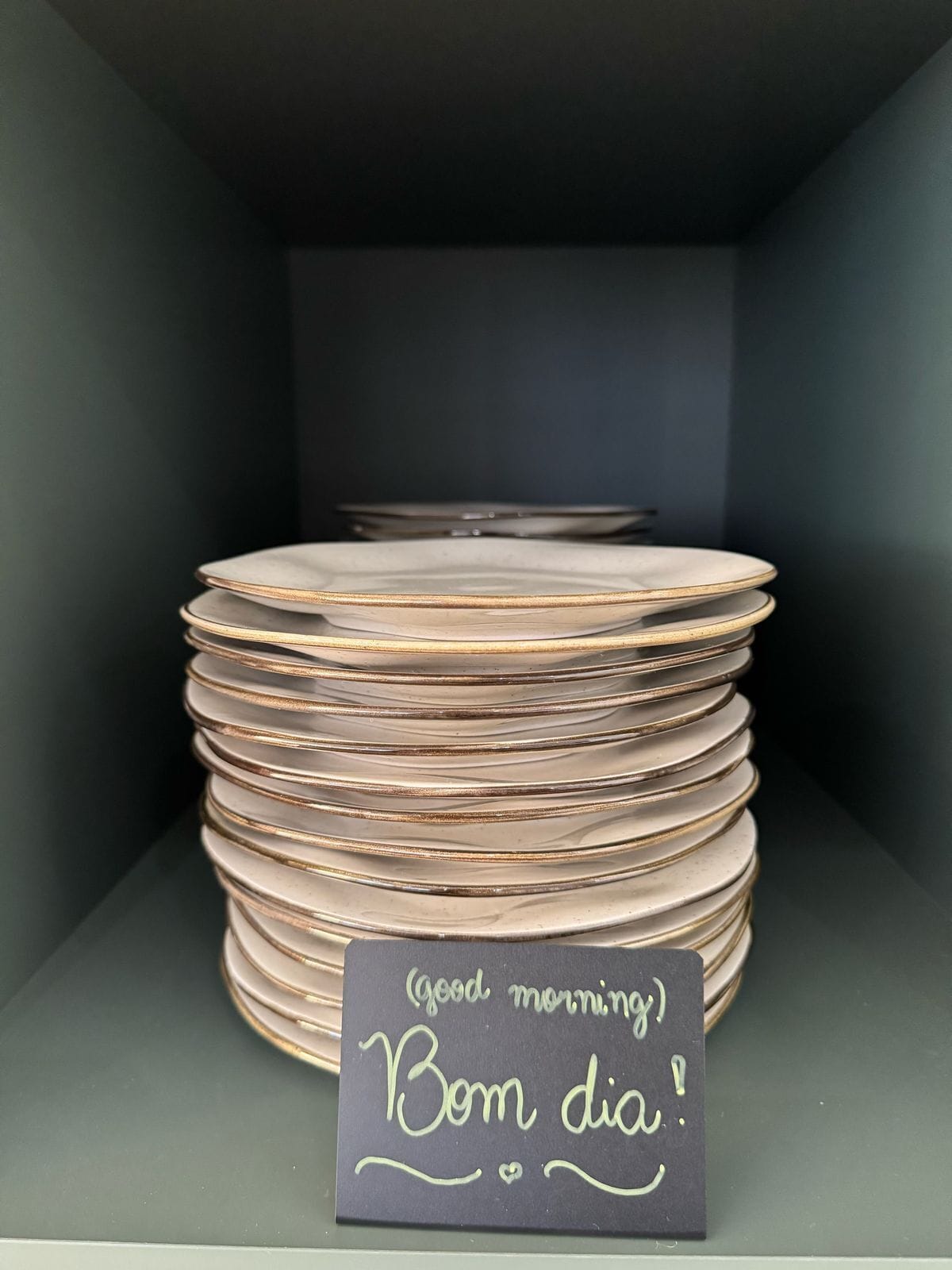 Una pila de platos con un letrero que dice '¡Buenos días! ¡Bom dia!'