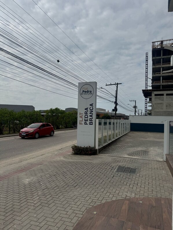 Señalización de 'Flat Pedra Branca', con un sendero pavimentado y un coche rojo que pasa.