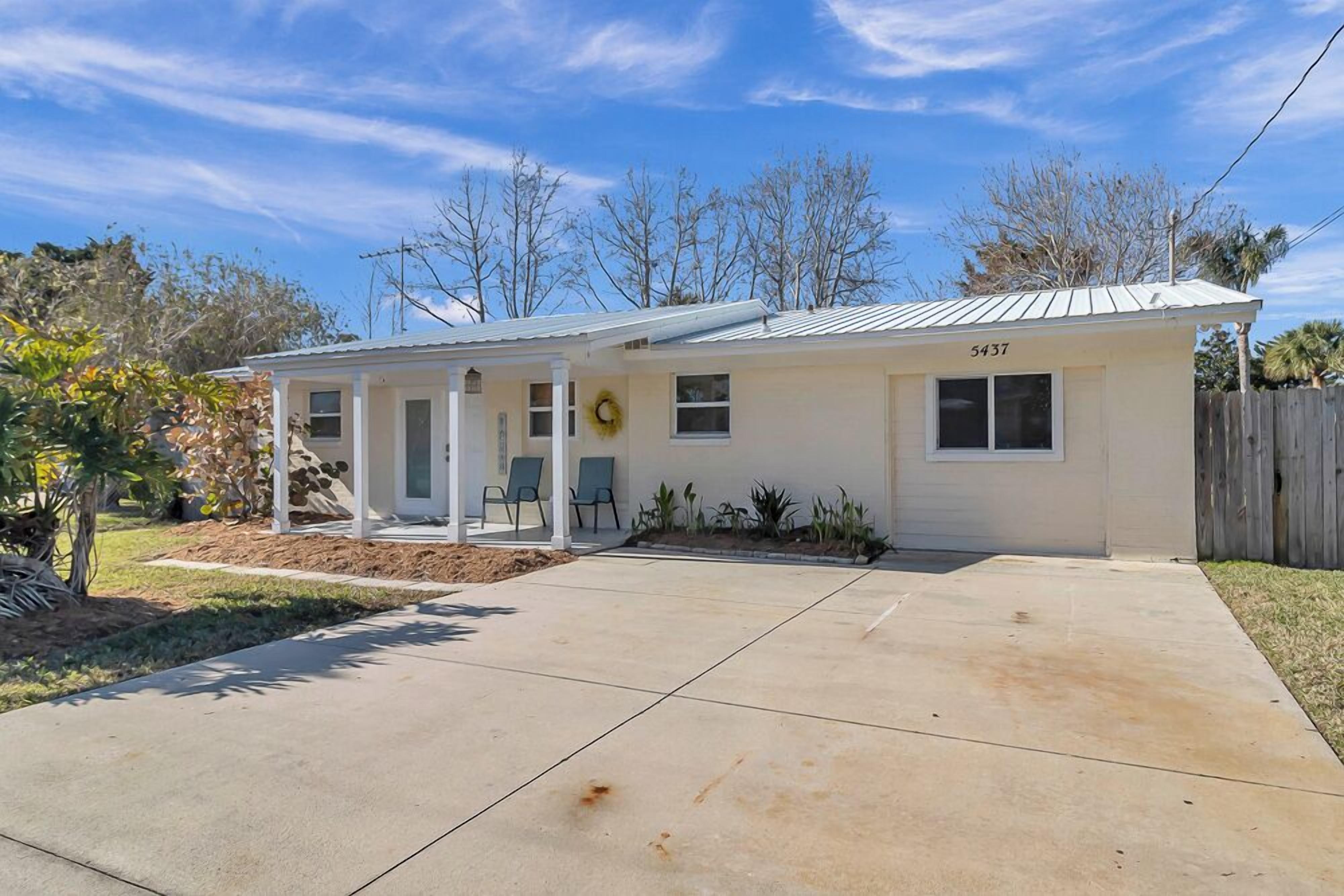 A single-story house with a covered porch, a number '5437' on the front, and a small garden area.