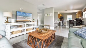 Una sala de estar con televisor, una mesa de madera y un sofá.