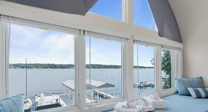 Ein Zimmer mit großen Fenstern und Blick auf ein Gewässer, eine Anlegestelle und ein Boot.