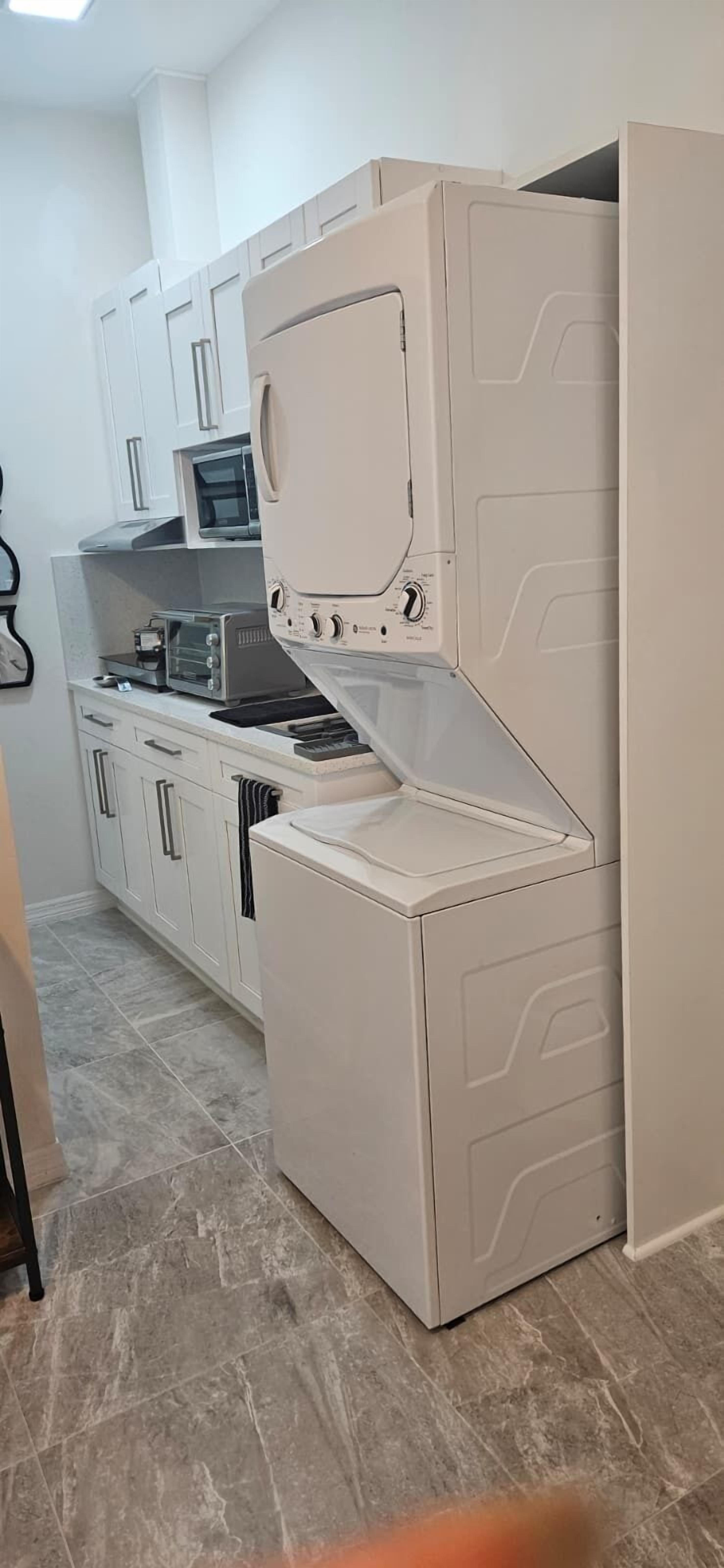 A compact kitchen with white cabinets, a microwave, a toaster, and a built-in oven.