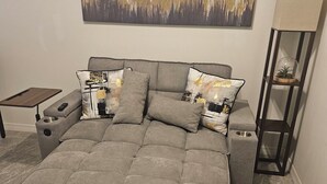 Een slaapkamer met een groot bed, een nachtkastje, een lamp en een schilderij aan de muur.