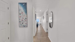 Ein Flur mit weißen Wänden, Holzboden und einem großen abstrakten Gemälde an der linken Wand.