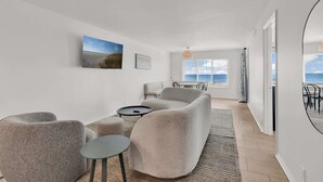 Ein modernes Wohnzimmer mit großem Fenster, einer Couch, einem Couchtisch und einem Teppich.
