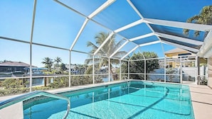 Ein klares, blaues Schwimmbecken mit Glasabdeckung, umgeben von Palmen und blauem Himmel.