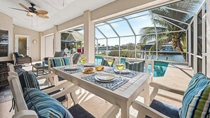 Ein Essbereich mit Blick auf den Pool, Außenmöbel und einem Deckenventilator.