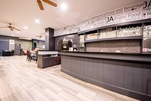 A modern restaurant interior with a bar area, wooden flooring, ceiling fans, and a wall with food-related words. - Sunday JA Plus Hotel (Pattaya)