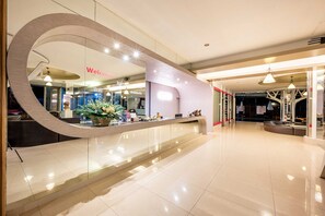A modern hotel lobby with a curved reception desk, a 'Welcome' sign, and a glass partition. - Sunday JA Plus Hotel (Pattaya)