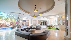 A spacious lobby with a curved seating area, a pool, and large windows. - Sunday JA Plus Hotel (Pattaya)