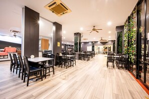 A spacious dining area with multiple tables and chairs, ceiling fans, and a modern interior design. - Sunday JA Plus Hotel (Pattaya)