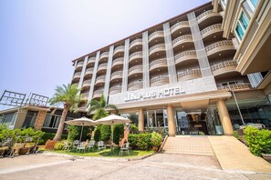 A multi-story hotel with a central entrance, outdoor seating area, and a well-maintained garden. - Sunday JA Plus Hotel (Pattaya)