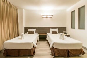 A hotel room with two beds, a wooden headboard, a small table, a nightstand, and a window. - Sunday JA Plus Hotel (Pattaya)