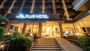 The entrance of J.A. PLUS HOTEL with a grand staircase leading up to the entrance, surrounded by lush greenery and a well-lit facade. - Sunday JA Plus Hotel (Pattaya)