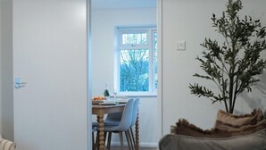 Una habitación con comedor, una ventana con vistas y una planta.