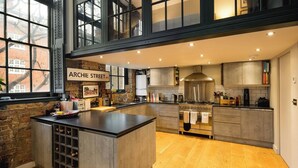 Een moderne keuken met een groot eiland, roestvrijstalen apparatuur en een bakstenen muur.