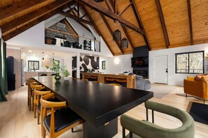 A spacious loft with a high ceiling, a large dining area, a kitchen, a living room with a fireplace, and a TV. - Pocono Family Retreat | Hot Tub, Sauna, Sleeps 14 (Blakeslee)