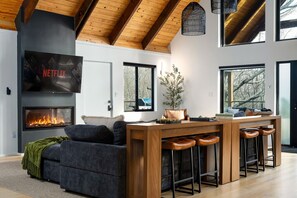 A modern living room with a fireplace, a TV, and a bar area. - Pocono Family Retreat | Hot Tub, Sauna, Sleeps 14 (Blakeslee)