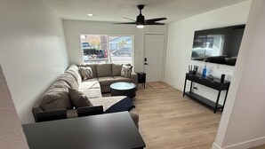Una sala de estar moderna con un sofá modular, una mesa de comedor y un televisor de pantalla plana montado en la pared.