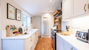 Uma cozinha moderna com armários brancos, uma ilha central e piso revestido de azulejos.