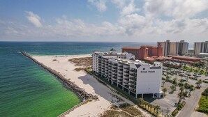 Un hotel frente al mar con varios balcones, una zona de piscina y vistas al océano.