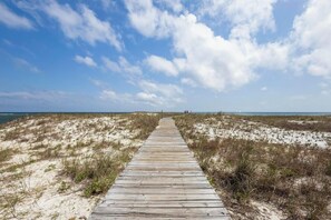 A wooden boardwalk leading to the beach, surrounded by sand dunes and sparse vegetation. - Beachfront Condo w/ Huge Balcony, Pools, Sauna & Gulf Views | BEACHBALL PROPERTIES (Orange Beach)