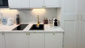 A modern kitchen with white cabinetry, a black sink, and a marble countertop. - Cozy 1-bedroom studio in amazing Katowice, 24h check-in (Katowice)