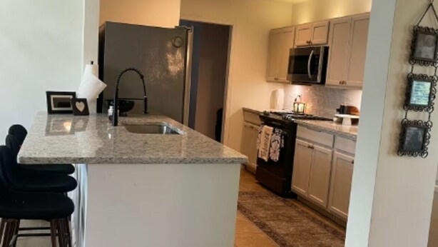A modern kitchen with a large island, stainless steel appliances, and a view into the dining area. - Spacious 4-bedroom house in beautiful Bartlesville with AC (Bartlesville)