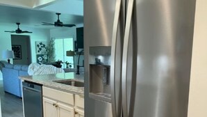 A stainless steel refrigerator in a kitchen with white cabinets and a granite countertop. - Spacious 4-bedroom house in beautiful Bartlesville with AC (Bartlesville)