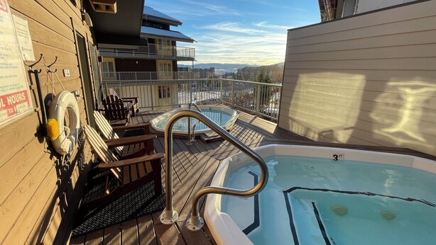 Un espace piscine sur le toit, comprenant un jacuzzi, une terrasse en bois et des sièges d’extérieur.