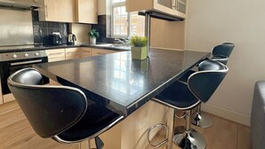 Una cucina moderna con isola centrale, sgabelli da bar e vista sulla città.