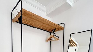 Una stanza con un mobiletto a scaffali in legno, uno specchio e una porta bianca.