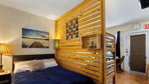 A hotel room with a bed, wooden slat wall paneling, a Buddha statue, a clock, and a door with an 'EXIT' sign. - Relaxing 1BR w/ BBQ, Patio and Convenient Access (Hollywood)