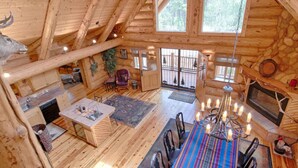 L’intérieur d’une cabane en rondins comprend un coin repas, une cuisine et une cheminée.