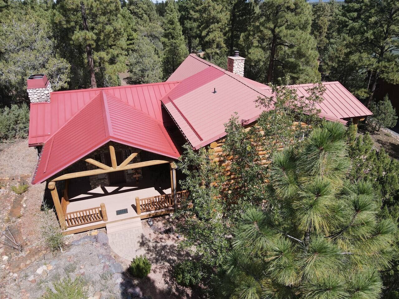 A lodge with a red roof, wooden deck, and stone chimney.