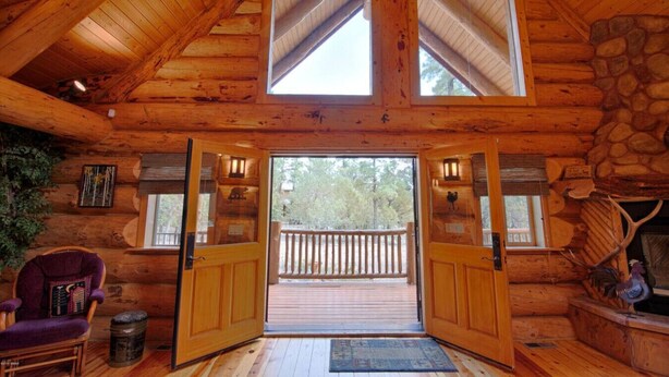 Une cabane en rondins avec un intérieur en bois, un mur en pierre et un balcon doté d’une balustrade.
