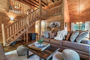 Ein Holzblockhaus-Innenraum mit Treppe, einer Sofagarnitur und einem Couchtisch.