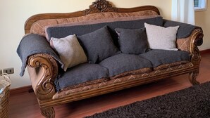 Een gezellige woonkamer met een houten bank, een donker vloerkleed en twee bloemschilderijen aan de muur.