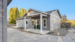 A two-story house with a covered porch, a front door, and a small front yard. - The Evergreen Escape - Spacious 1 bed Unit (Kennewick)
