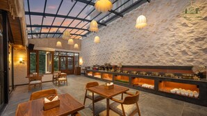 Un restaurante con pared de piedra, mesas de madera y lámparas colgantes.