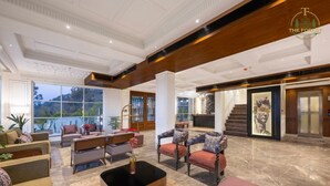 Un hall espacioso con techo alto, ventanas grandes y un mostrador de recepción.