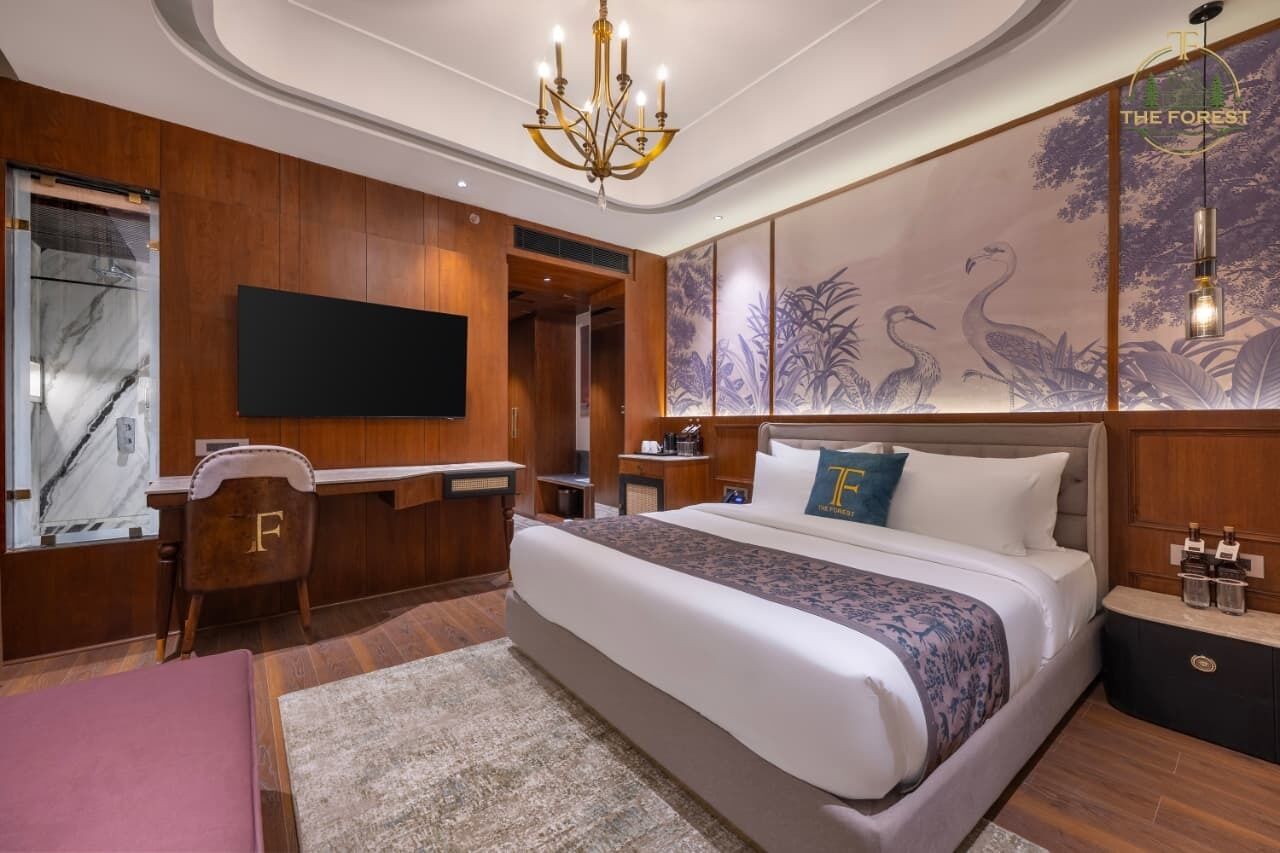 A hotel room with a large bed, a desk, a TV, and a wall with a nature-themed mural.