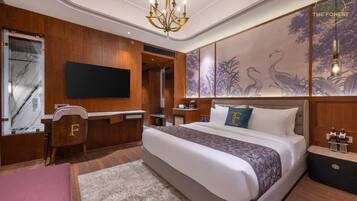 A hotel room with a large bed, a desk, a TV, and a wall with a nature-themed mural.